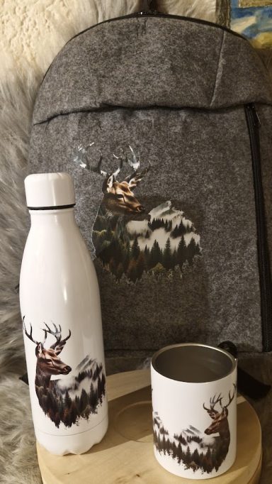 Grauer Rucksack mit Hirsch-Applikation, daneben eine weiße Wasserflasche und Tasse.